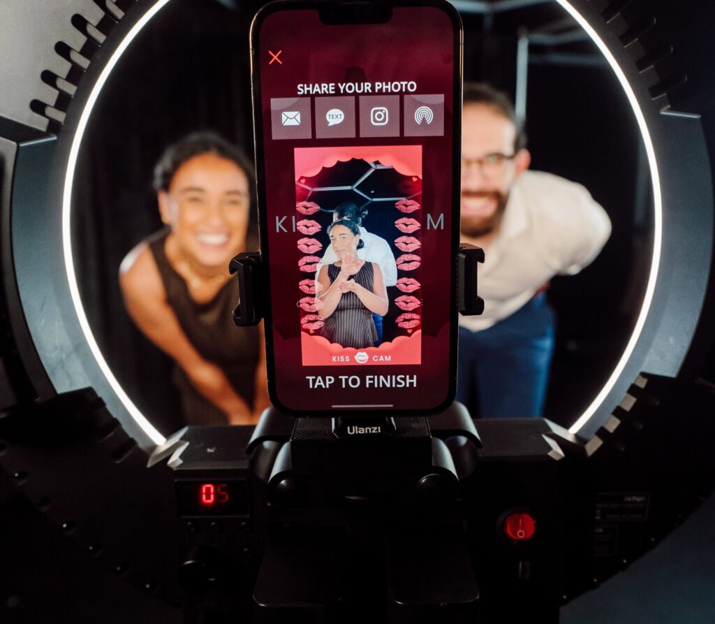 A man and woman taking a kiss cam picture with a phone