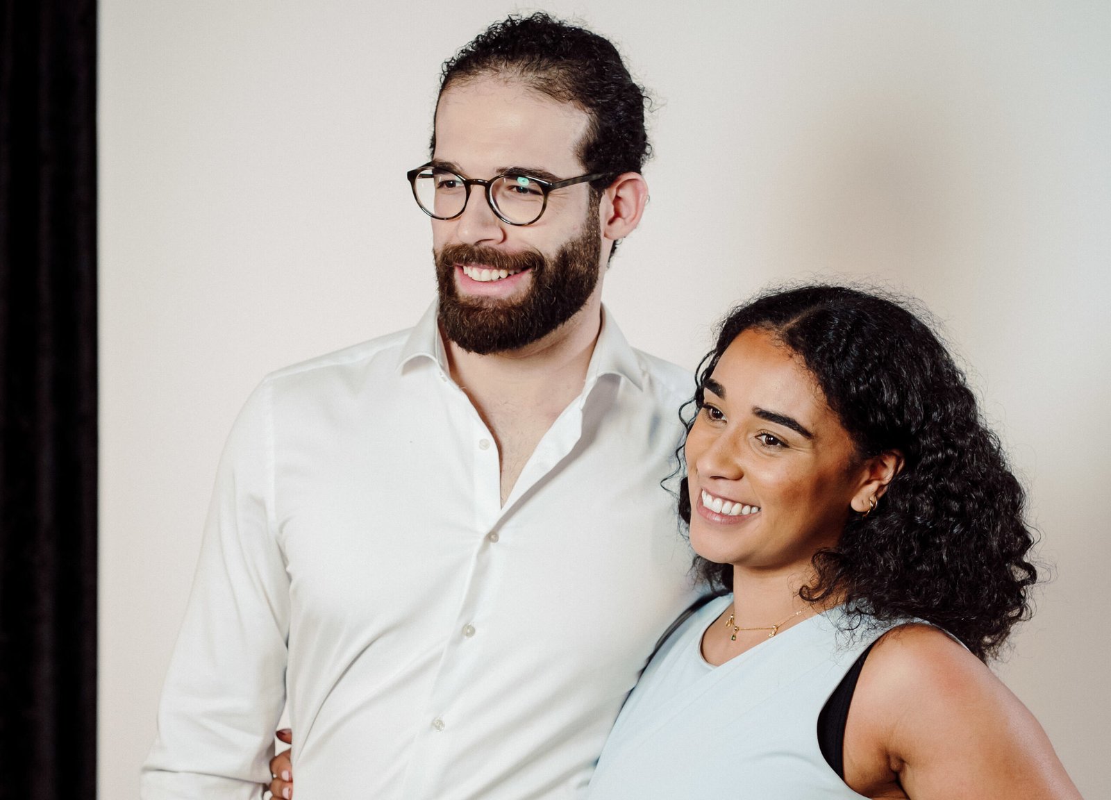 Couple posing for a photo in front of a white backdrop